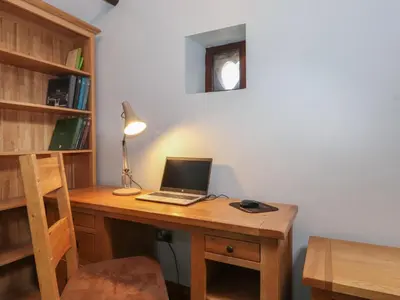 a laptop computer sitting on a wooden desk with a lamp at The Gardener's Bothy in Penrith