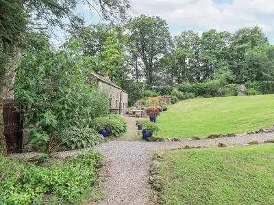 a garden with a stone path leading to a house at The Gardener's Bothy in Penrith