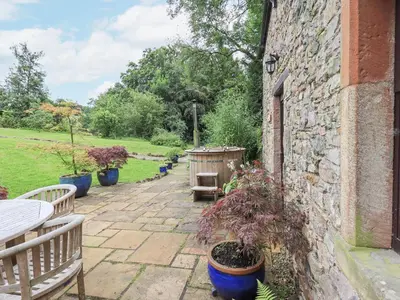 a patio with potted plants and a stone wall at The Gardener's Bothy in Penrith