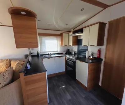 a small kitchen with white cabinets and a couch at Woodside, Meadows Retreat, Cockermouth in Plumbland