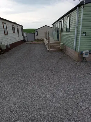 a large gravel parking lot between two mobile homes at Green Dream in Cockermouth