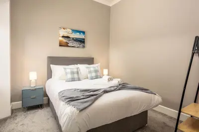 a bedroom with a bed with a blue nightstand and a painting at South Beach View in Troon