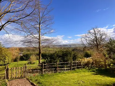 a wooden fence in a field with a tree at Archie the shepherd’s hut in Penruddock