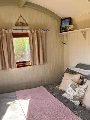 a bedroom with a bed and a window at Archie the shepherd’s hut in Penruddock