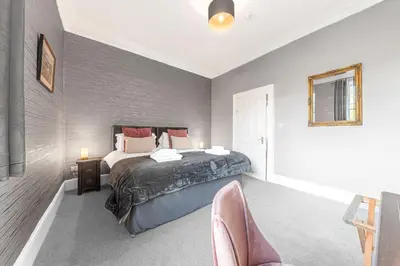 a bedroom with a bed and chairs in it at Ashbrooke Apartment Keswick at The Lairbeck in Keswick