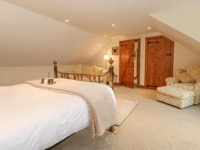 a bedroom with a large bed and a chair at Glen View in Dumfries