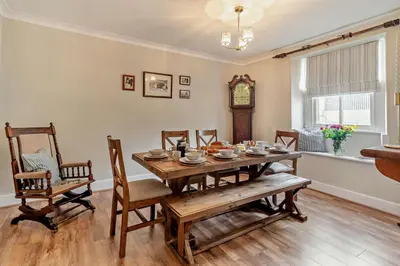 a dining room with a table and chairs and a clock at 4 Bed in Kinniside oc-c28854 in Frizington