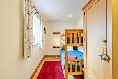 a bedroom with a bunk bed and a red rug at 2 Bed in Irthington oc-v28308 in Irthington
