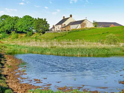 a house on top of a hill next to a pond at 2 Bed in Irthington oc-v28308 in Irthington
