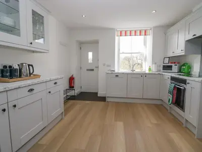 a kitchen with white cabinets and a wooden floor at Dalegarth Hall Farm Cottage 1 in Holmrook