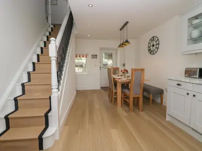 a kitchen and dining room with a staircase with a table and chairs at Dalegarth Hall Farm Cottage 1 in Holmrook