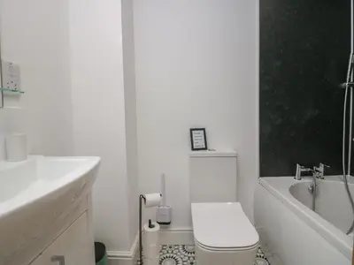 a white bathroom with a toilet and a bath tub at Dalegarth Hall Farm Cottage 1 in Holmrook