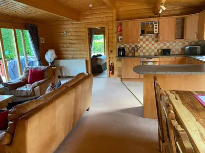 a living room with a couch and a kitchen at Kipplochan in Dalbeattie