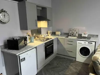 a kitchen with a stove and a washer and dryer at The Print Room, 1 Bedroom Ground Floor Apartment in Carlisle