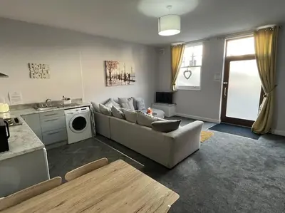 a living room with a couch and a dishwasher at The Print Room, 1 Bedroom Ground Floor Apartment in Carlisle