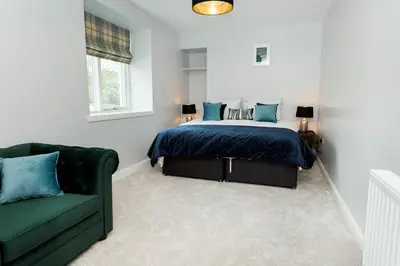 a bedroom with a bed and a green couch at Disdow House in Gatehouse of Fleet