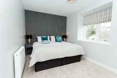 a white bedroom with a large bed with blue pillows at Disdow House in Gatehouse of Fleet