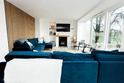 a living room with a blue couch and a tv at Disdow House in Gatehouse of Fleet