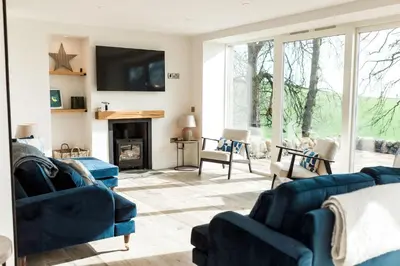 a living room with two blue couches and a fireplace at Disdow House in Gatehouse of Fleet