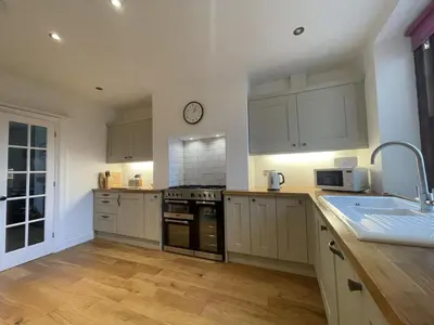 a kitchen with white cabinets and a clock on the wall at Fell View in Portinscale