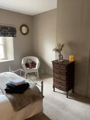 a bedroom with a bed and a dresser and a chair at Stunning 2-bedroomed Cottage in Cockermouth