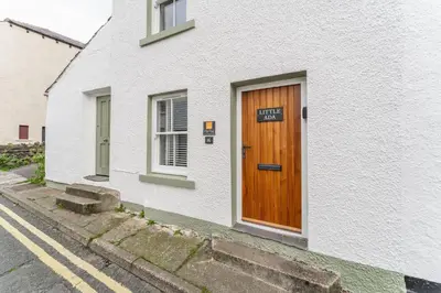 a white house with a wooden door on a street at Little Ada in Keswick