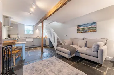 a living room with a couch and a kitchen at Little Ada in Keswick