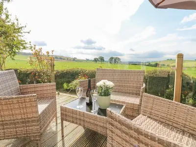 a patio with chairs and a table with wine glasses at Plot 32 in Carlisle