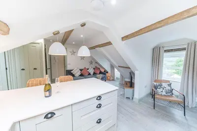 a kitchen with a white counter and a living room at Otterbield, Derwent House, Portinscale in Portinscale