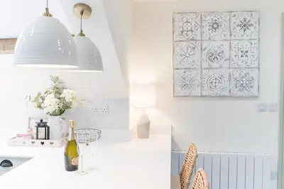 a kitchen with a white counter with a vase of flowers at Otterbield, Derwent House, Portinscale in Portinscale