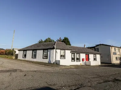 an old white house with a red door on a street at Smithy House in Dumfries