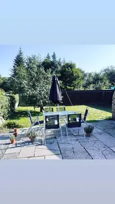 a table and chairs and an umbrella on a patio at Odea Hot tub Holiday Cottage in Dumfries