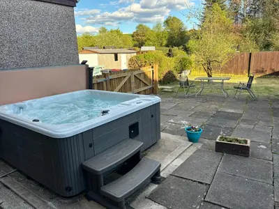 a hot tub on a patio with a table at Odea Hot tub Holiday Cottage in Maxwelltown