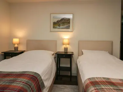 two beds in a room with two lamps on tables at The Barn in Seascale