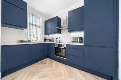 a kitchen with blue cabinets and a wooden floor at Central Gretna Luxury 4 bed in Gretna