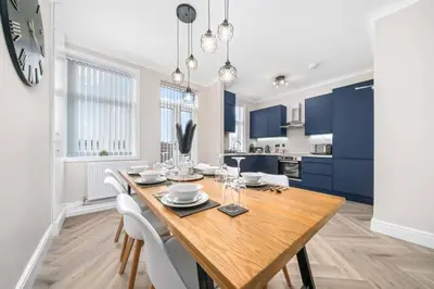 a dining room with a wooden table and blue cabinets at Central Gretna Luxury 4 bed in Gretna