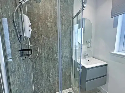 a bathroom with a shower and a sink at Flag Cottage in Carsethorn