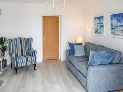 a living room with a couch and a chair at Flag Cottage in Carsethorn