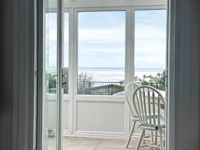 a window with a chair and a view of the ocean at Flag Cottage in Carsethorn