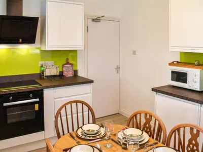 a kitchen with a table with chairs and a microwave at Teazles in Peel