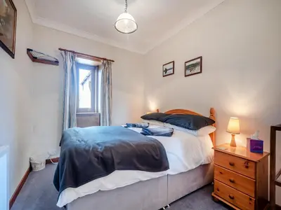 a bedroom with a large bed and a window at Kilbride Cottage-Uk46886 in Kilmory