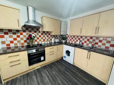 a kitchen with wooden cabinets and a washer and dryer at Curwen Apartment - 2 Bedrooms - Sleeps 6 in Workington