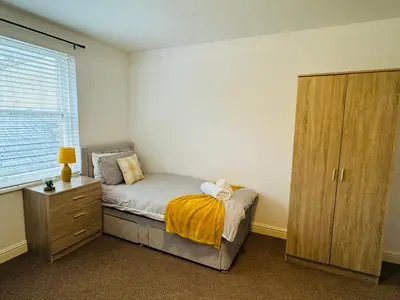a bedroom with a bed and a cabinet and a window at Curwen Apartment - 2 Bedrooms - Sleeps 6 in Workington