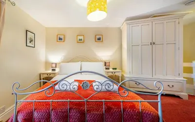 a bedroom with a bed with a red comforter at Beagle Cottage in Keswick