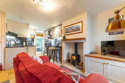 a living room with a red couch and a fireplace at Beagle Cottage in Keswick