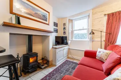 a living room with a red couch and a fireplace at Beagle Cottage in Keswick