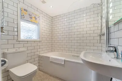 a white bathroom with a tub and a toilet and a sink at Beagle Cottage in Keswick