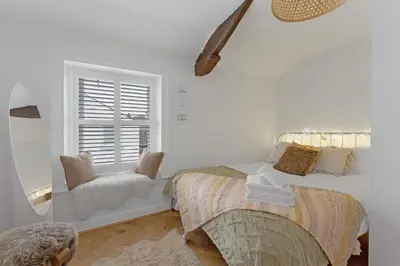 a bedroom with a bed and a mirror and a window at Darwin Cottage in Keswick