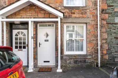 a brick house with a white door and windows at Ratstone Cottage in Keswick
