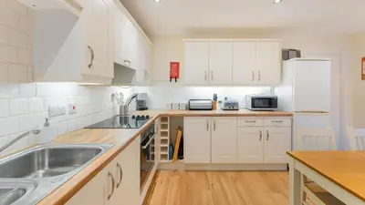 a kitchen with white cabinets and a sink at Sunny Cottage in Keswick